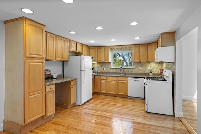 kitchen featuring light wood-style floors, backsplash, white appliances, and a sink