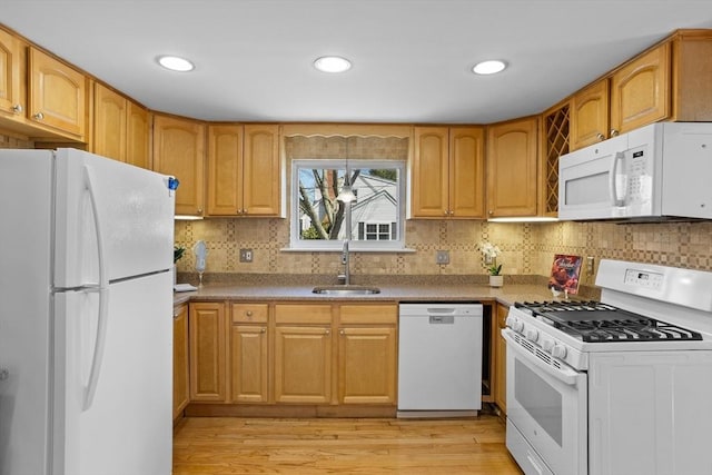 kitchen featuring white appliances, tasteful backsplash, a sink, and light wood-type flooring