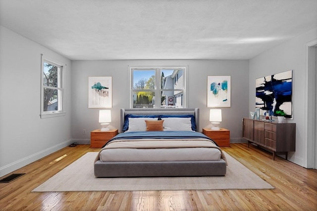 bedroom with visible vents, baseboards, and wood finished floors