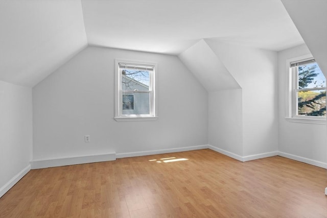bonus room featuring light wood-style floors, baseboards, a wealth of natural light, and vaulted ceiling