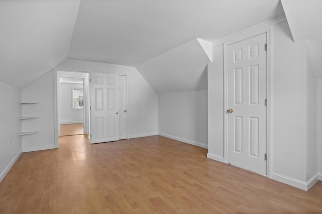 bonus room featuring light wood-style floors, baseboards, and lofted ceiling