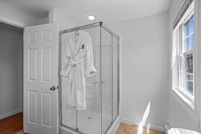 bathroom with baseboards, a shower stall, and baseboard heating