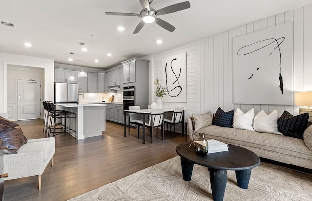 living room with wood walls, dark hardwood / wood-style floors, and ceiling fan