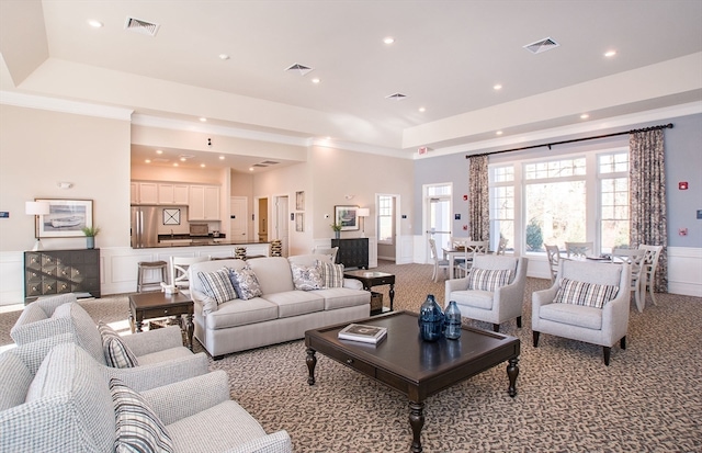 living room featuring light colored carpet and a raised ceiling