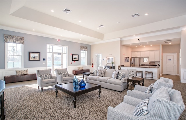 living room featuring light colored carpet, crown molding, and a raised ceiling