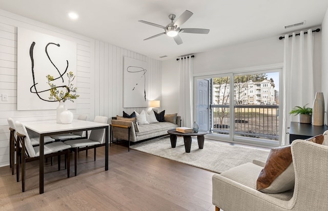 living room with wood walls, hardwood / wood-style flooring, and ceiling fan