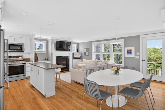 53 W Vine St Unit A, Provincetown, MA 02657 - dining space featuring a glass covered fireplace, light wood-type flooring, crown molding, healthy amount of natural light, and recessed lighting