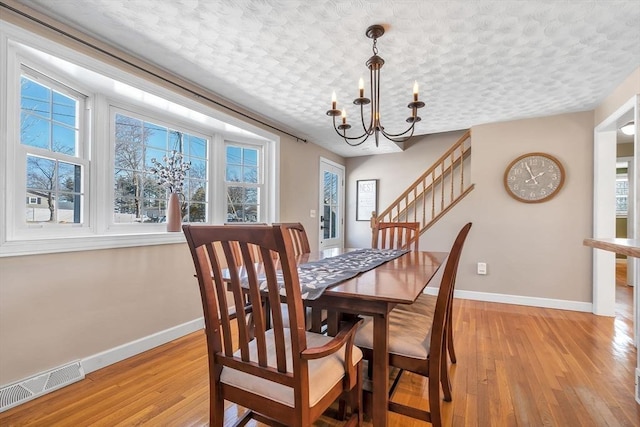 dining space with a chandelier, visible vents, light wood finished floors, and baseboards