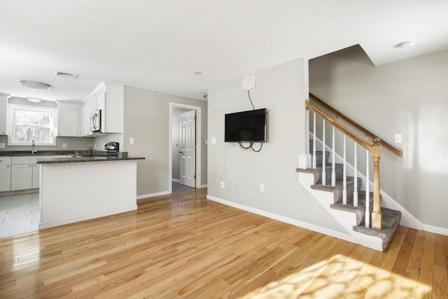 unfurnished living room with sink and light hardwood / wood-style floors