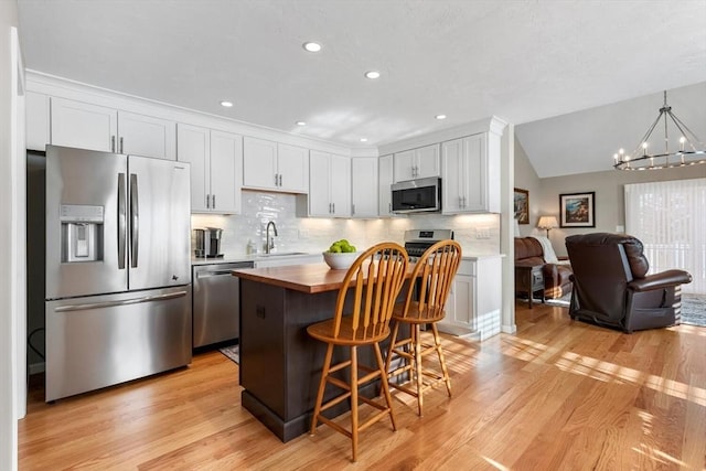 kitchen with white cabinets, appliances with stainless steel finishes, tasteful backsplash, a notable chandelier, and a kitchen bar