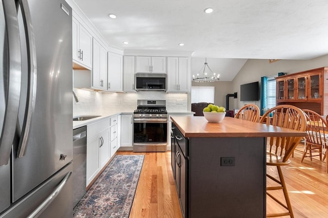 kitchen with stainless steel appliances, backsplash, decorative light fixtures, a breakfast bar, and white cabinets