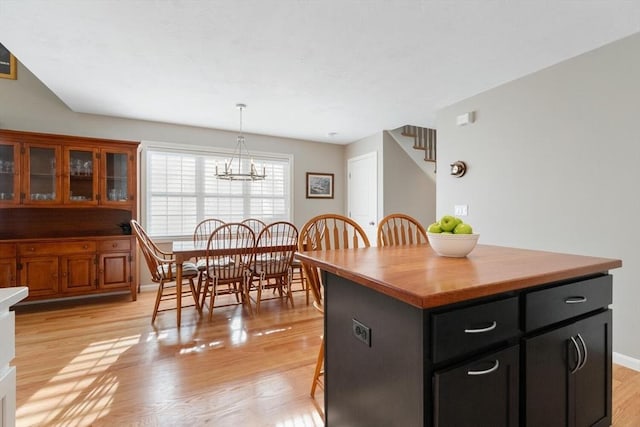 kitchen featuring a breakfast bar, pendant lighting, a chandelier, light hardwood / wood-style floors, and a kitchen island