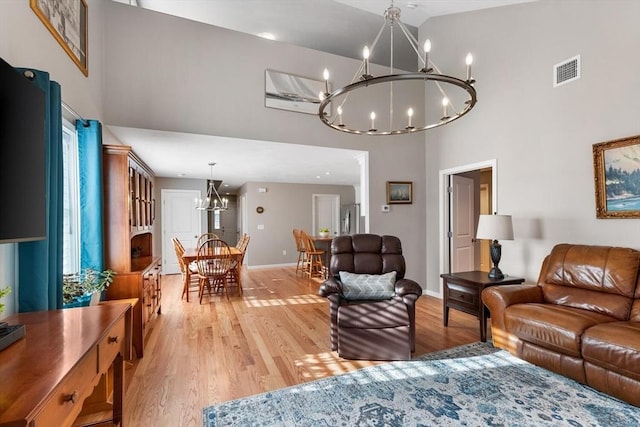 living room with an inviting chandelier, high vaulted ceiling, and light hardwood / wood-style flooring