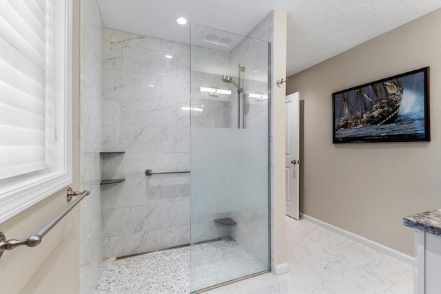 bathroom with a tile shower and vanity