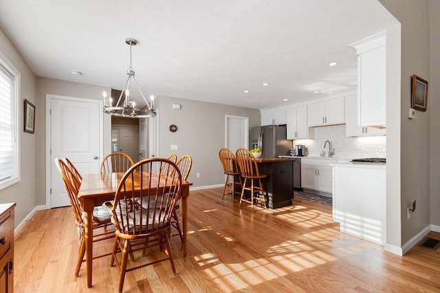 dining space featuring an inviting chandelier, light hardwood / wood-style flooring, and sink