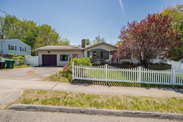 ranch-style house featuring a garage, a fenced front yard, driveway, and a chimney