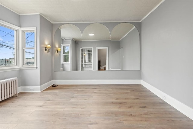 309 E Eagle St, Boston, MA 02128 - spare room featuring arched walkways, ornamental molding, wood finished floors, radiator heating unit, and baseboards