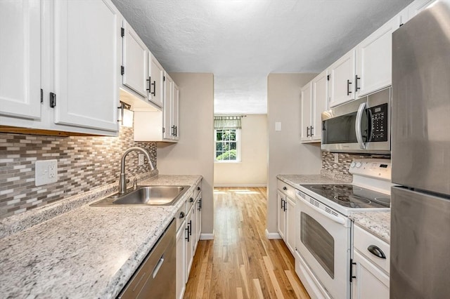 47 Patrick Rd Unit 47, Tewksbury, MA 01876 - kitchen with stainless steel appliances, light wood finished floors, a sink, white cabinets, and baseboards