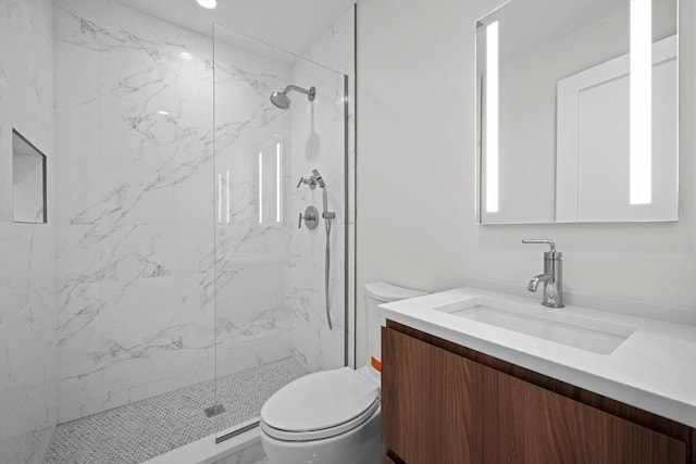 bathroom featuring toilet, tiled shower, and vanity