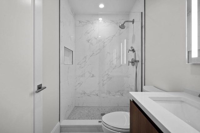 bathroom featuring toilet, vanity, and a tile shower