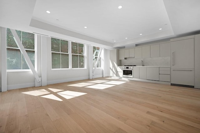 unfurnished living room with light hardwood / wood-style floors and a raised ceiling