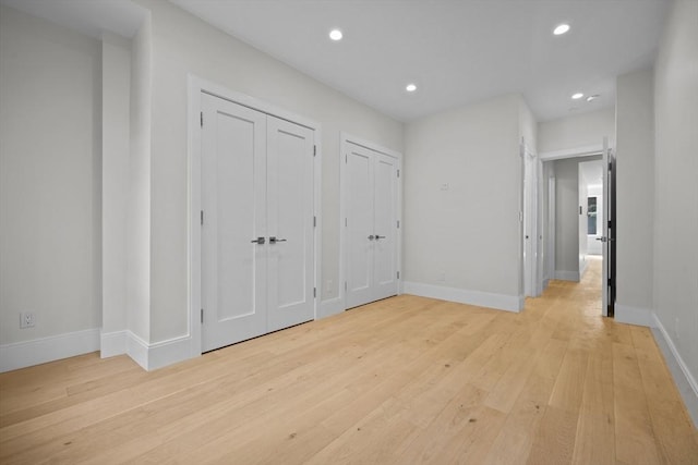 unfurnished bedroom with multiple closets and light hardwood / wood-style flooring