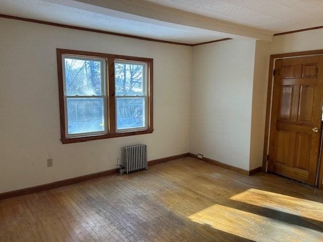 spare room featuring light wood-type flooring, radiator, and crown molding