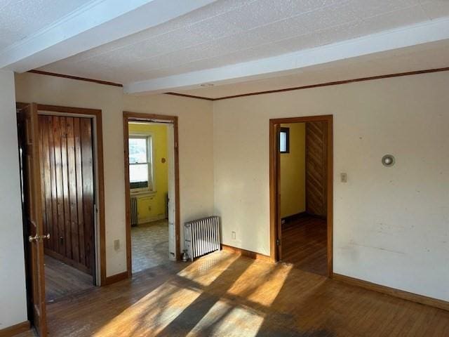 spare room featuring beam ceiling, radiator, and dark hardwood / wood-style flooring