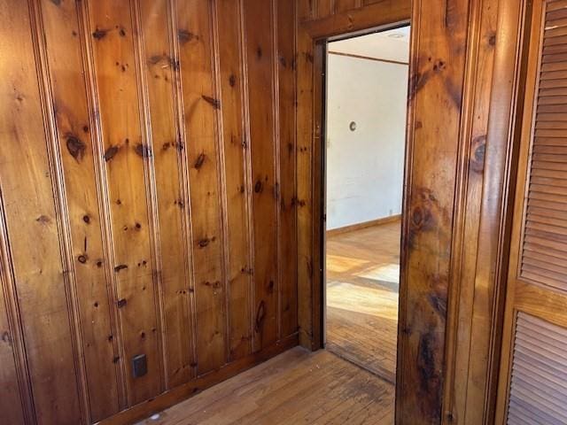 corridor with wood walls and light hardwood / wood-style flooring