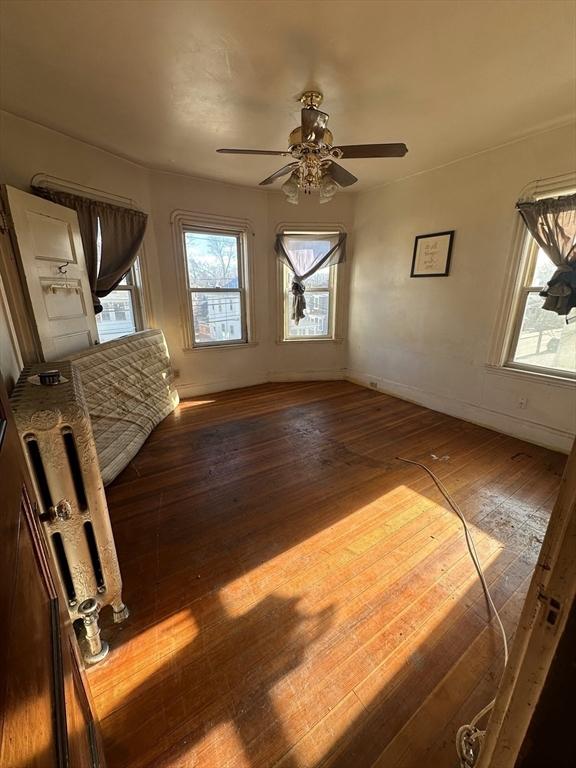 interior space with a ceiling fan, baseboards, and wood finished floors