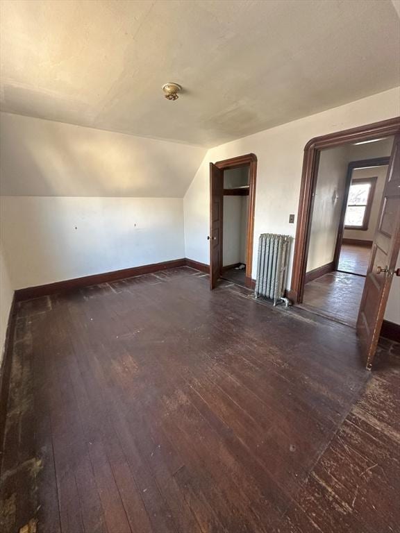 additional living space featuring lofted ceiling, radiator heating unit, dark wood finished floors, and baseboards