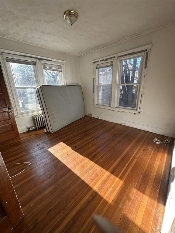 spare room with dark wood-style floors, radiator heating unit, and baseboards