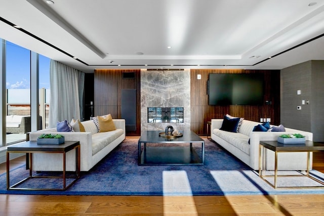 living room with dark hardwood / wood-style floors, a raised ceiling, and a wall of windows