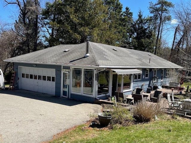 view of front of property featuring a garage, driveway, and a shingled roof
