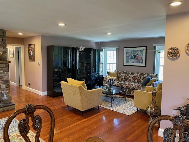 living area featuring baseboards, a stone fireplace, wood finished floors, and recessed lighting