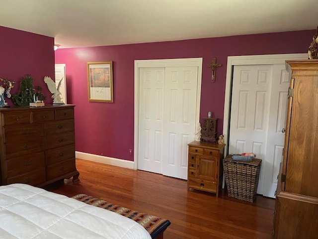 bedroom featuring baseboards, multiple closets, and wood finished floors