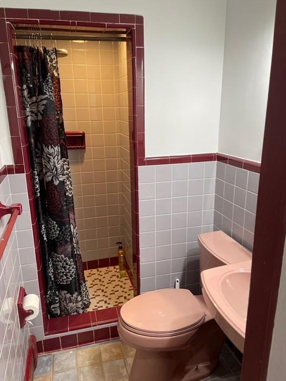 full bathroom with a shower stall, tile walls, toilet, and a wainscoted wall
