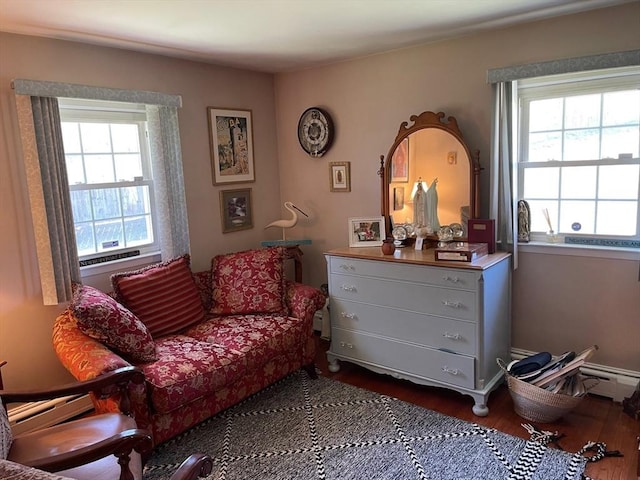 sitting room with a baseboard heating unit and dark wood-type flooring