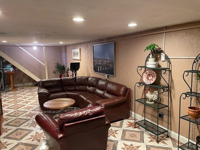living area featuring a textured wall, baseboards, recessed lighting, and stairway
