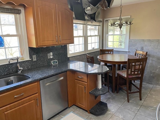 kitchen featuring a sink, dark stone counters, a chandelier, dishwasher, and light tile patterned floors