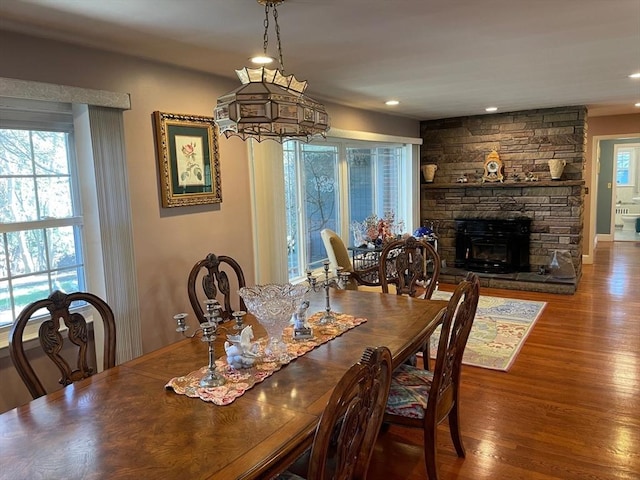 dining space with wood finished floors, a fireplace, and a healthy amount of sunlight