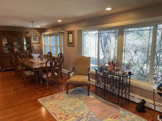 dining area with wood finished floors, a baseboard heating unit, baseboards, a notable chandelier, and recessed lighting