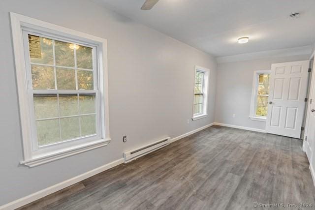 spare room featuring ceiling fan, baseboard heating, and dark hardwood / wood-style flooring