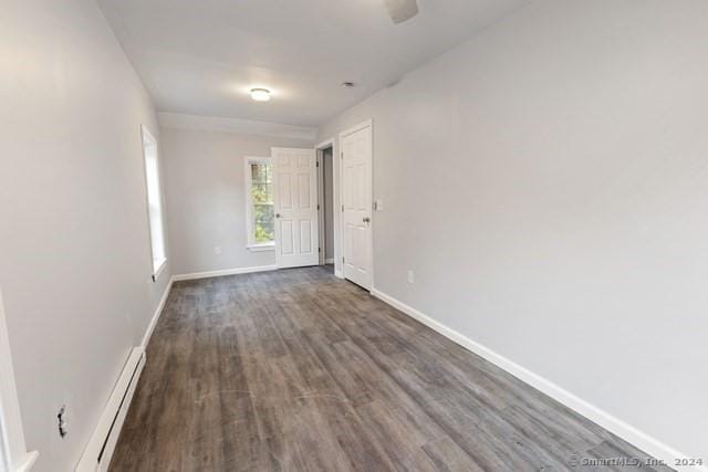 empty room with dark hardwood / wood-style floors and baseboard heating