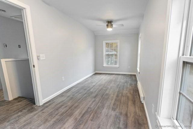 unfurnished room featuring ceiling fan, a baseboard heating unit, and dark hardwood / wood-style floors