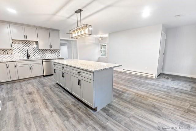 kitchen with hanging light fixtures, baseboard heating, stainless steel dishwasher, sink, and a kitchen island