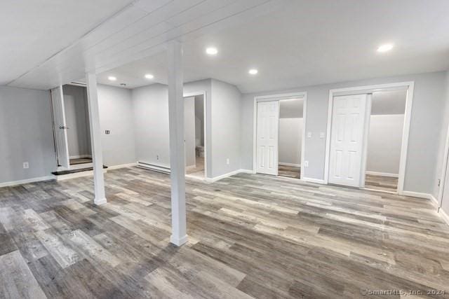 basement featuring hardwood / wood-style flooring and a baseboard heating unit