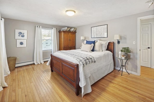 bedroom featuring light wood-type flooring and a baseboard heating unit