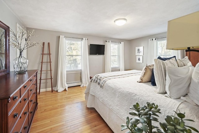 bedroom with a baseboard radiator, light hardwood / wood-style floors, and multiple windows