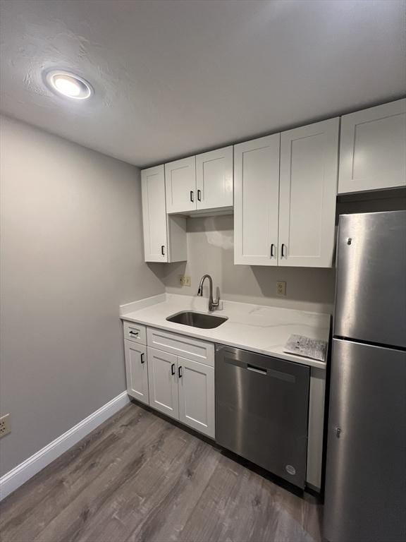 kitchen featuring a sink, baseboards, light countertops, dark wood-style floors, and stainless steel appliances
